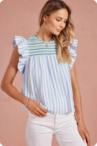 Woman wearing a blue and white striped top with ruffled sleeves against a pink background