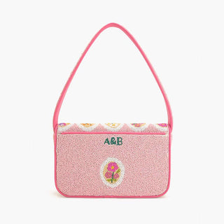 Pink glittery handbag with floral design and initials on a white background