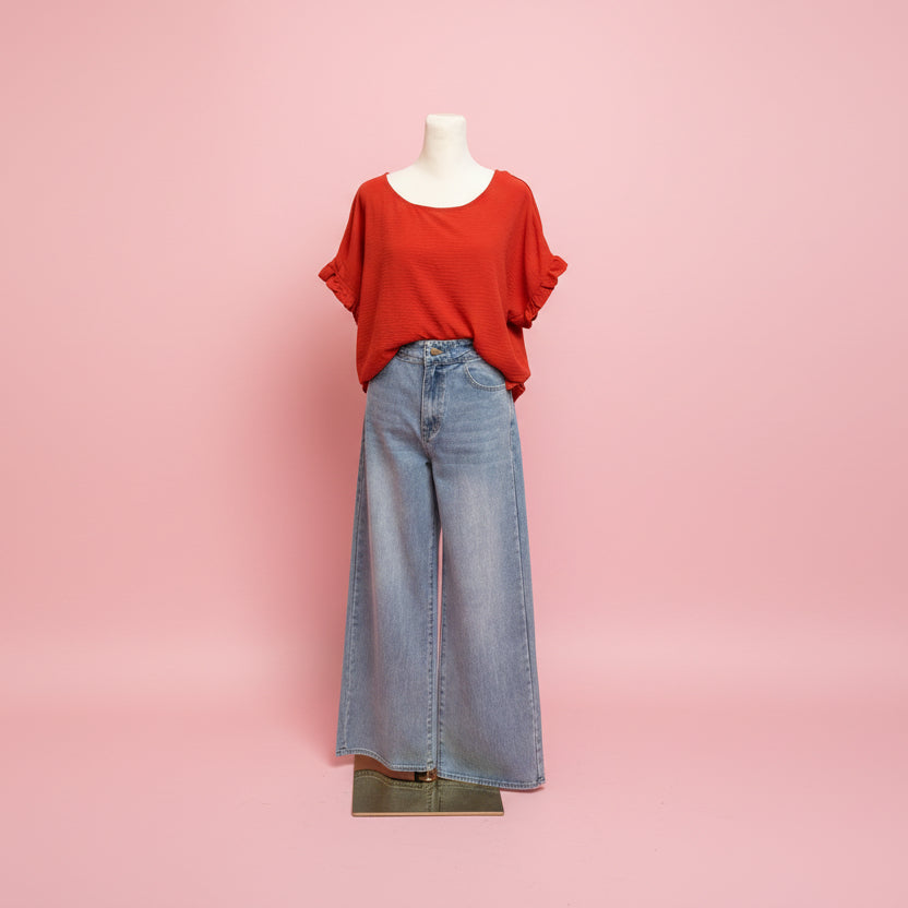 Mannequin wearing a red top and blue jeans on a pink background.