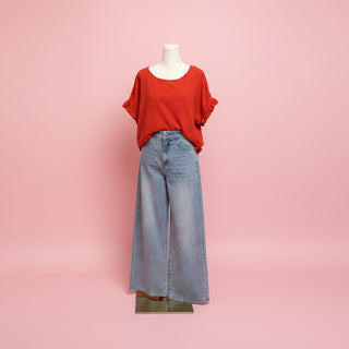 Mannequin wearing a red top and blue jeans on a pink background.
