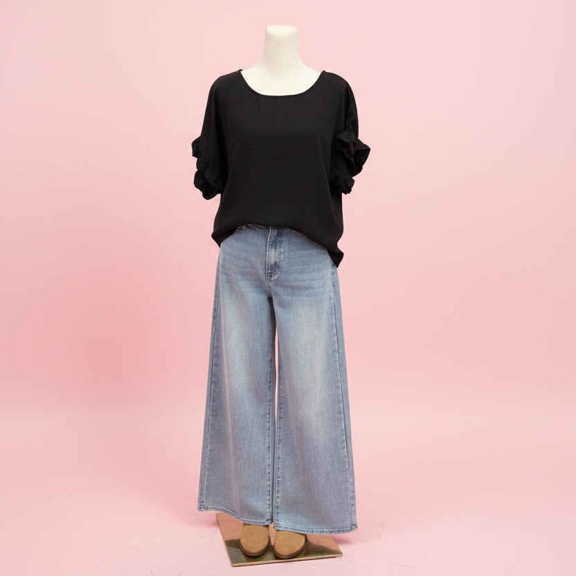 Black t-shirt and jeans on a mannequin against a pink wall.