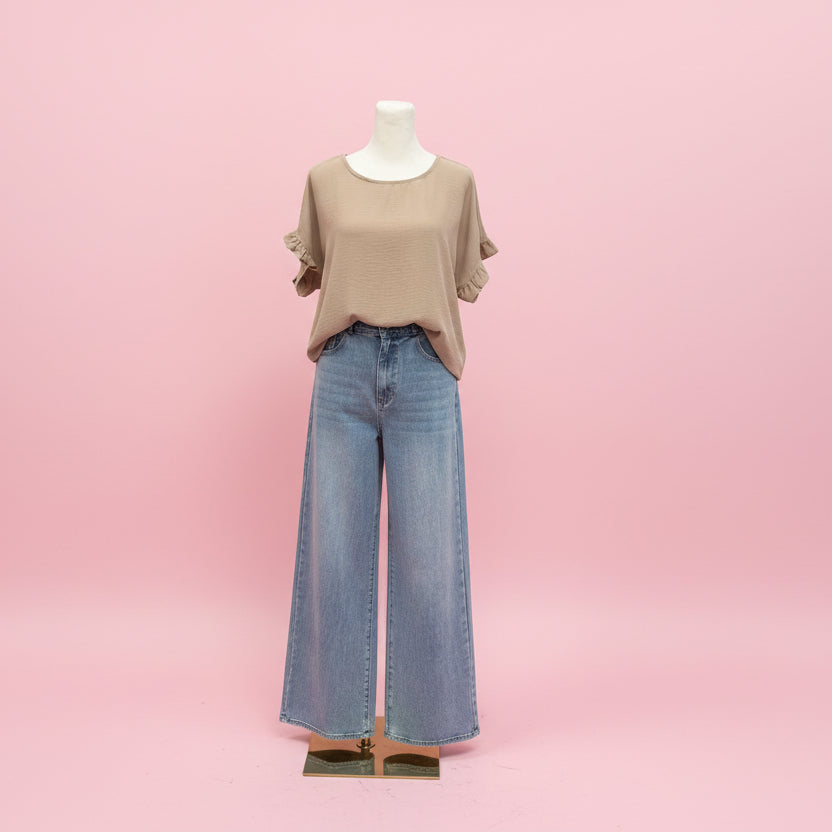 Mannequin wearing a beige top and blue jeans on a pink background