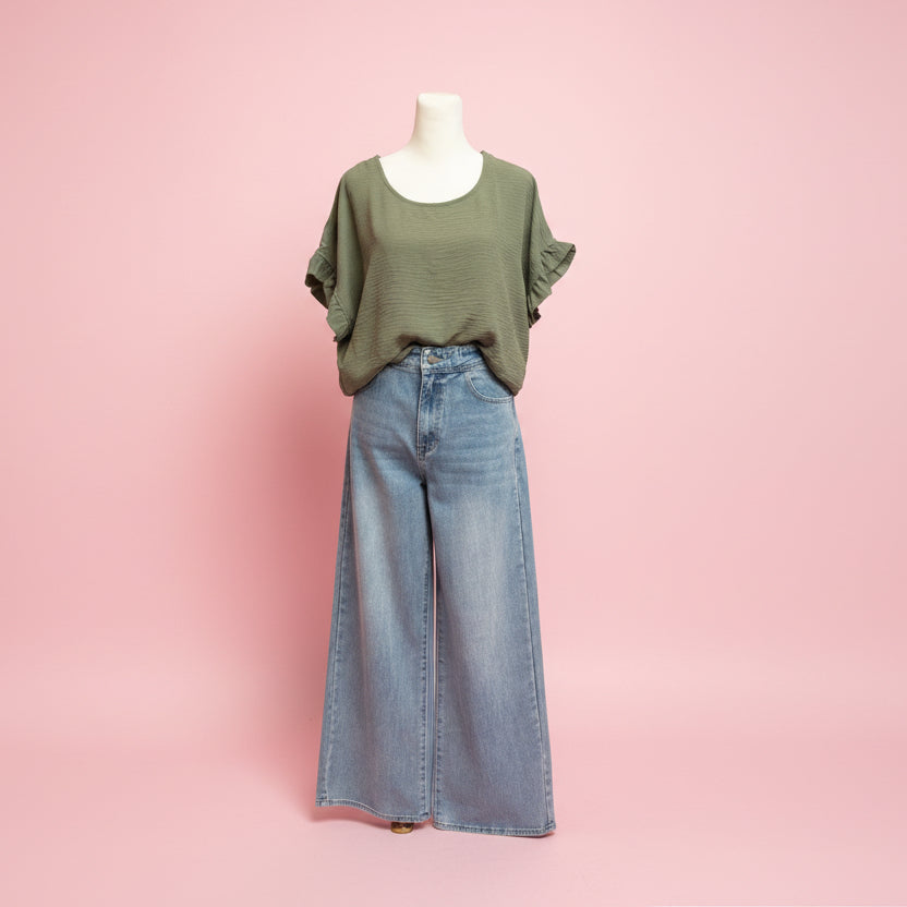 Mannequin wearing a green top and blue jeans on a pink background