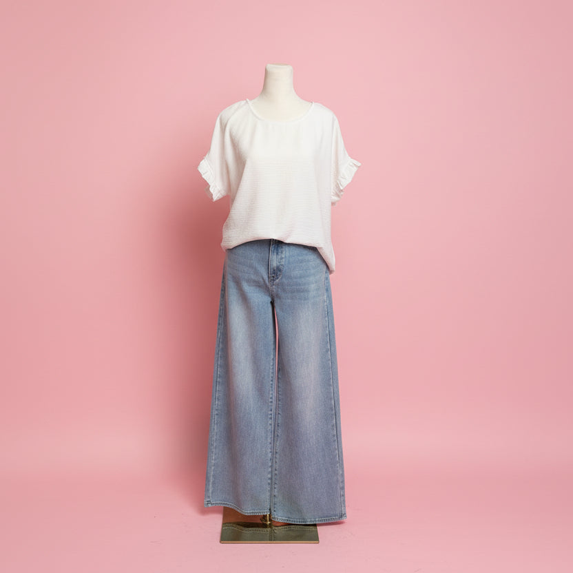 Mannequin wearing a white shirt and light blue jeans on a pink background.