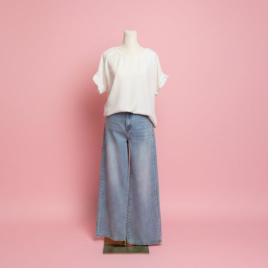 Mannequin wearing a white shirt and light blue jeans on a pink background.