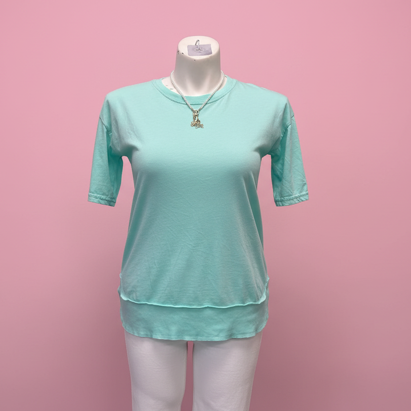 Turquoise t-shirt on a mannequin against a pink background