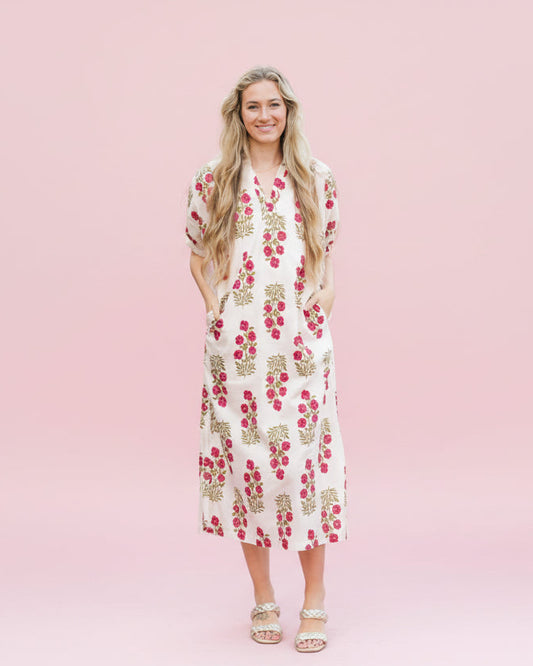 Woman in a floral dress standing on a cobblestone street with an American flag in the background.