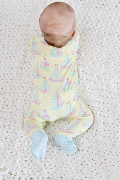 Baby wearing a pastel sailboat patterned onesie on a textured white surface
