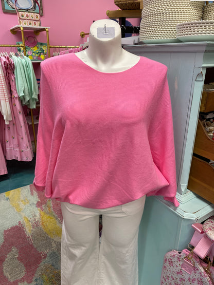 Mannequin wearing a pink sweater and white pants in a store setting