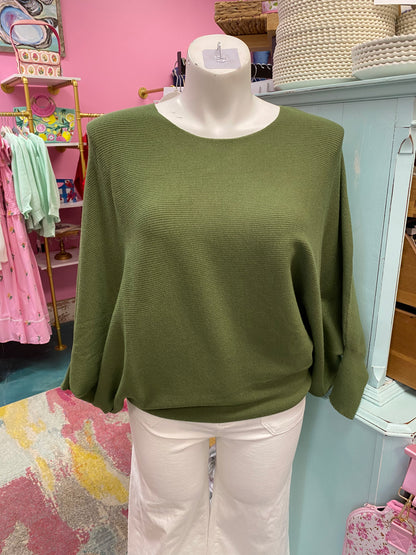 Green sweater on a mannequin with a pink store interior in the background