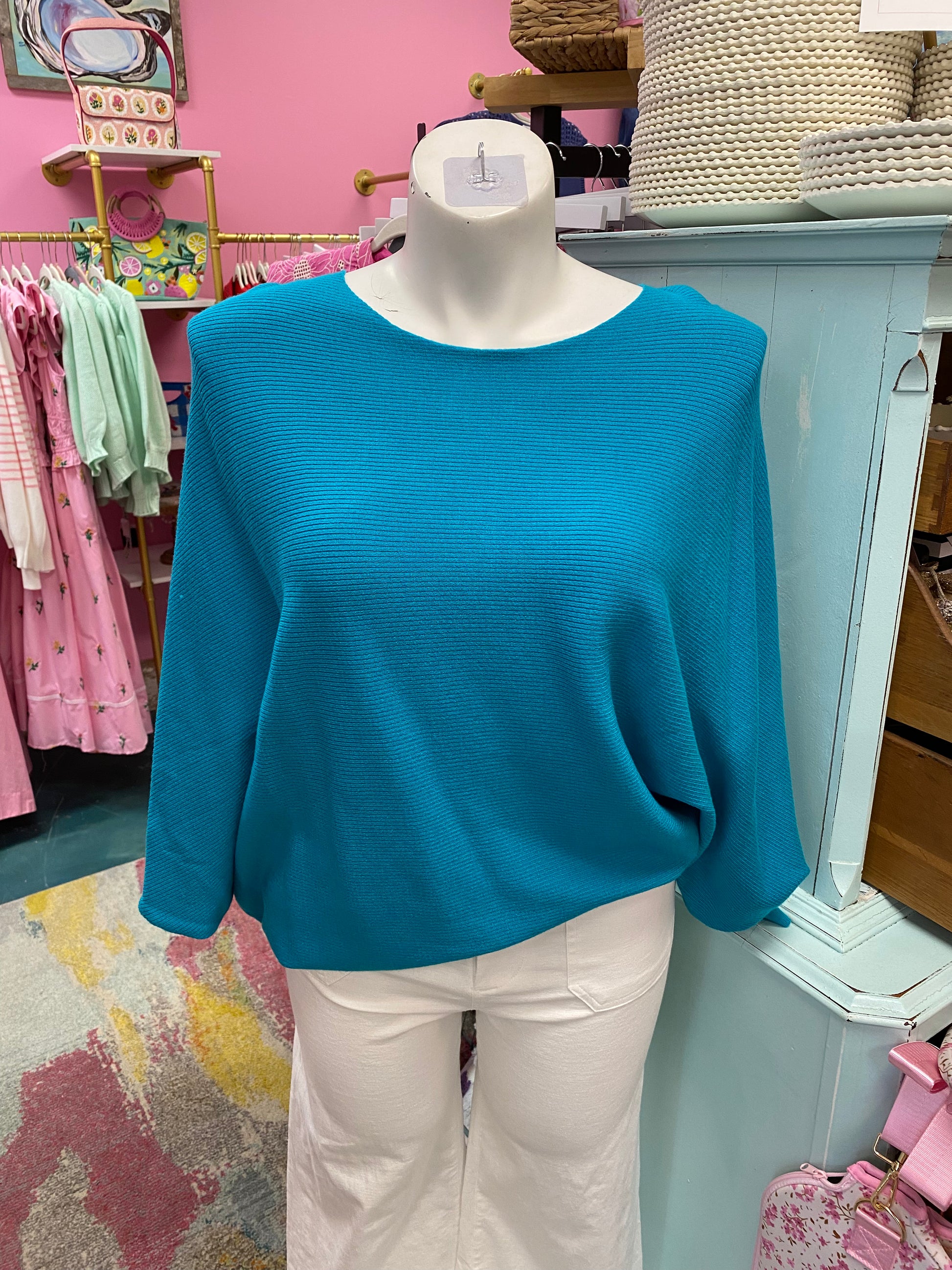 Mannequin wearing a blue sweater and white pants in a store setting