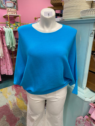 Mannequin wearing a blue top and white pants in a store setting