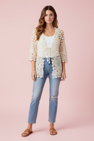 Model wearing a beige lace cardigan over a white top and denim pants 