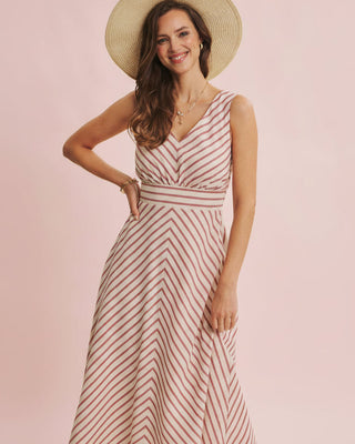 Woman wearing a striped dress and straw hat on a pink background