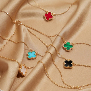 Gold necklaces with clover pendants on a satin background