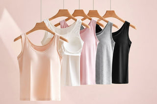 Set of tank tops in various colors hanging on wooden hangers against a light background