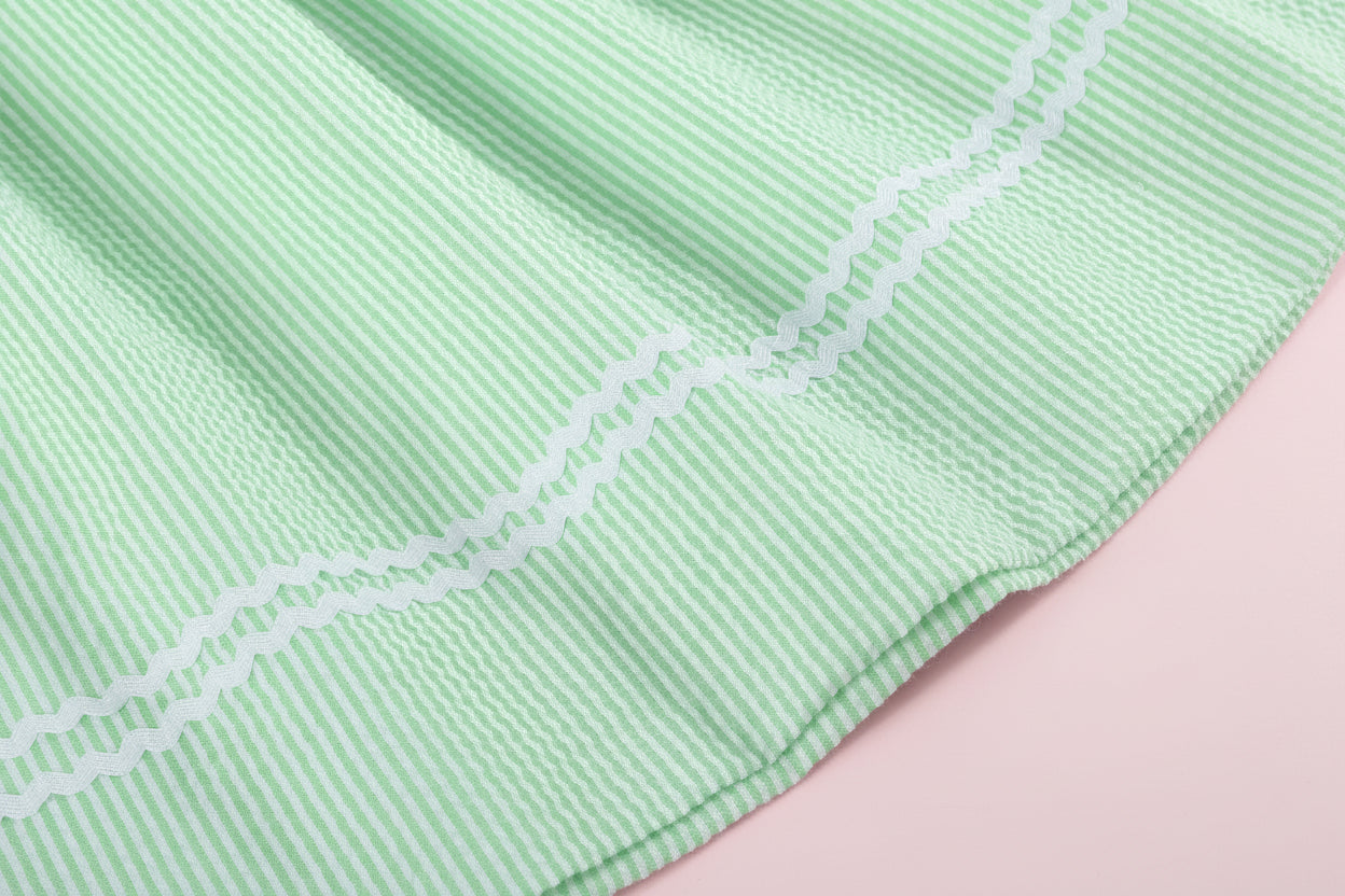 Close-up of a light green fabric with white stitching on a pink background