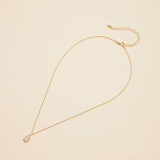 Gold Birthstone Pendant Necklace on a beige background. 