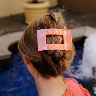 Person with a bun wearing a pink hair clip in an indoor setting
