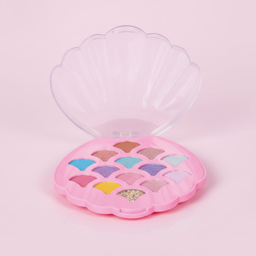 Makeup palette shaped like a shell with colorful shades on a pink background