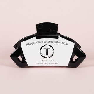 Black hair clip with a label on a pink background
