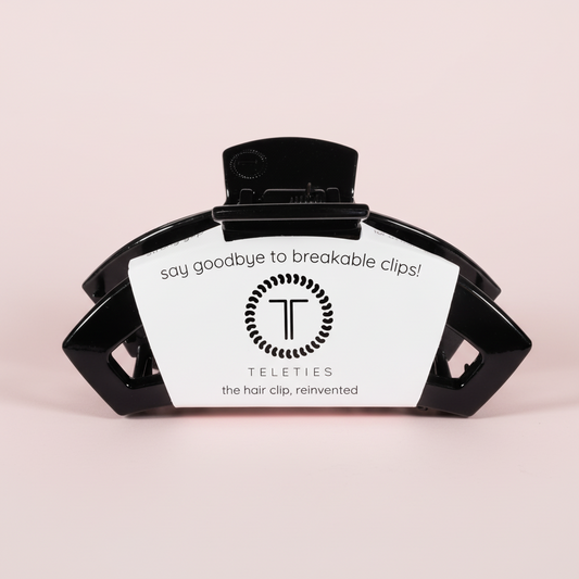 Black hair clip with a label on a pink background