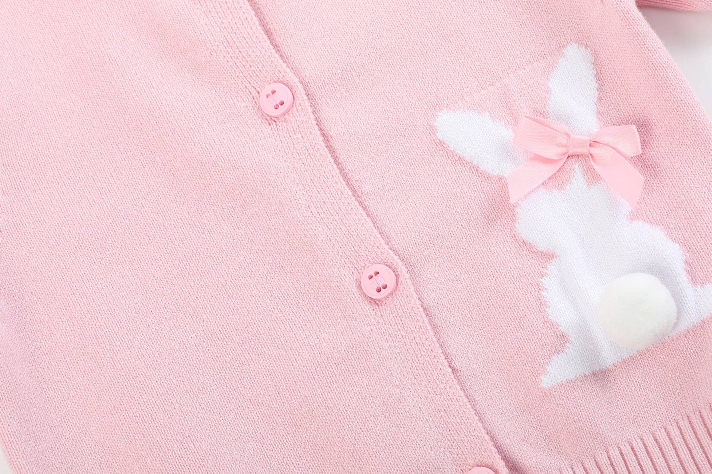 Pink cardigan with a bunny patch and bow on a light pink background