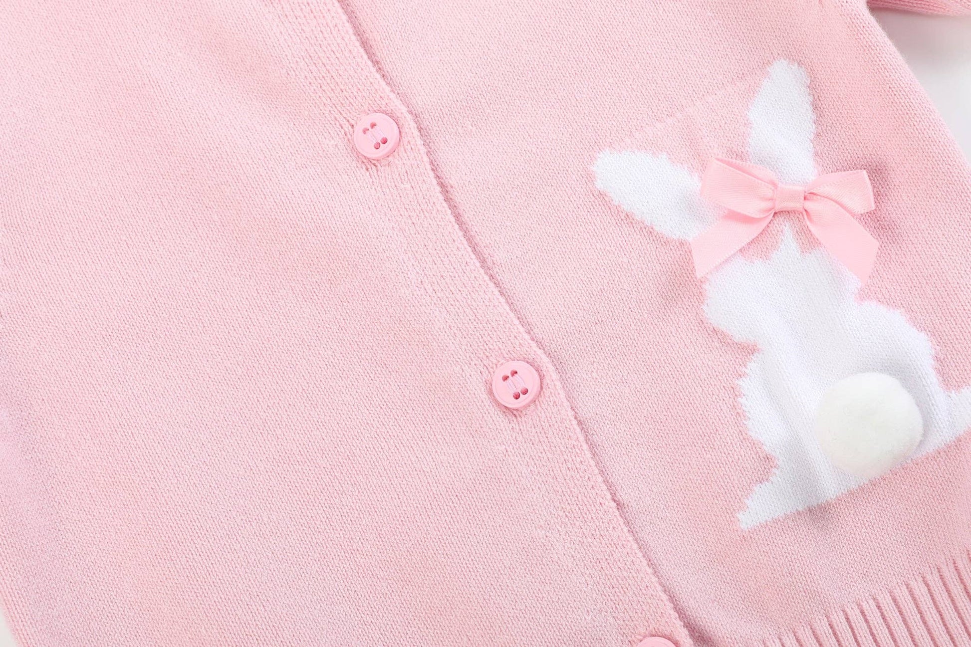 Pink cardigan with a bunny patch and bow on a light pink background