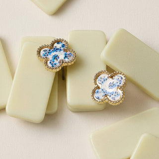 Gold earrings with blue pattern on a beige block