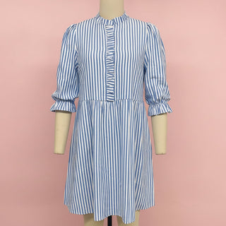 Blue and white striped dress on a mannequin against a pink background