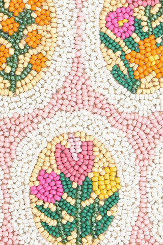 Close-up of a beaded pattern with floral designs in pastel colors on a white background.