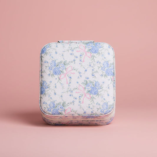 Floral-patterned jewelry travel case on a pink background