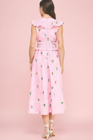 Woman wearing a pink dress with floral pattern on a pink background