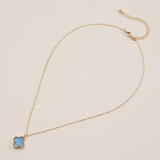 Gold necklace with a clover pendant on a light pink background