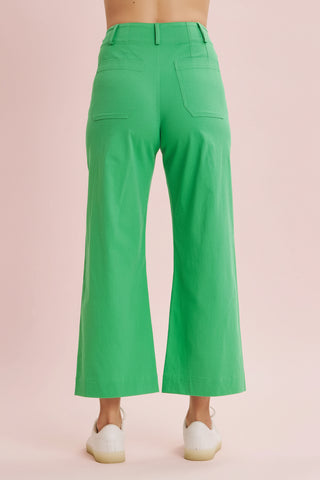 Green wide-leg pants worn by a person on a pink background