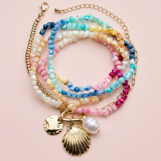 Colorful beaded bracelets with shell charms on a pink background