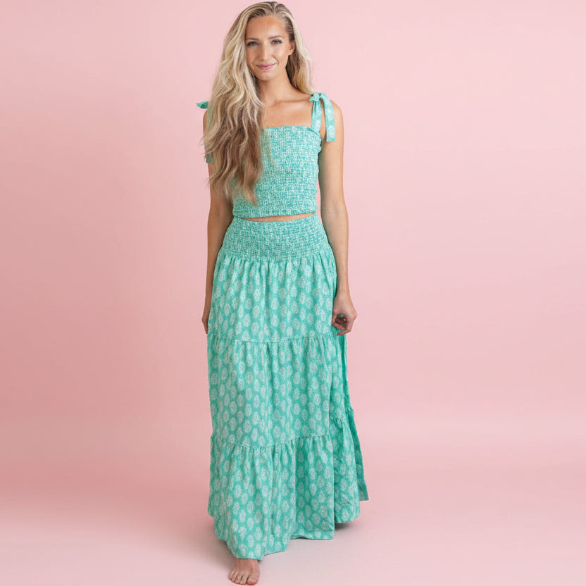 Woman wearing a green floral dress against a pink background