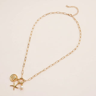 Gold necklace with starfish charm on a light beige background