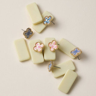 Four pairs of earrings on a light pink background.