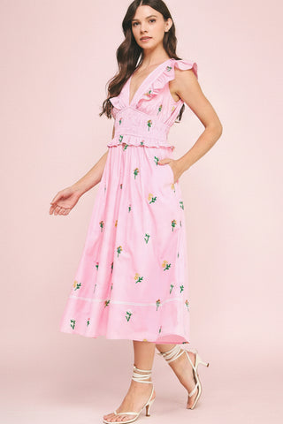 Woman wearing a pink floral dress against a pink background