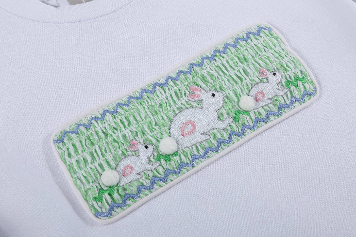 Embroidered patch with bunnies on grass design on a white background